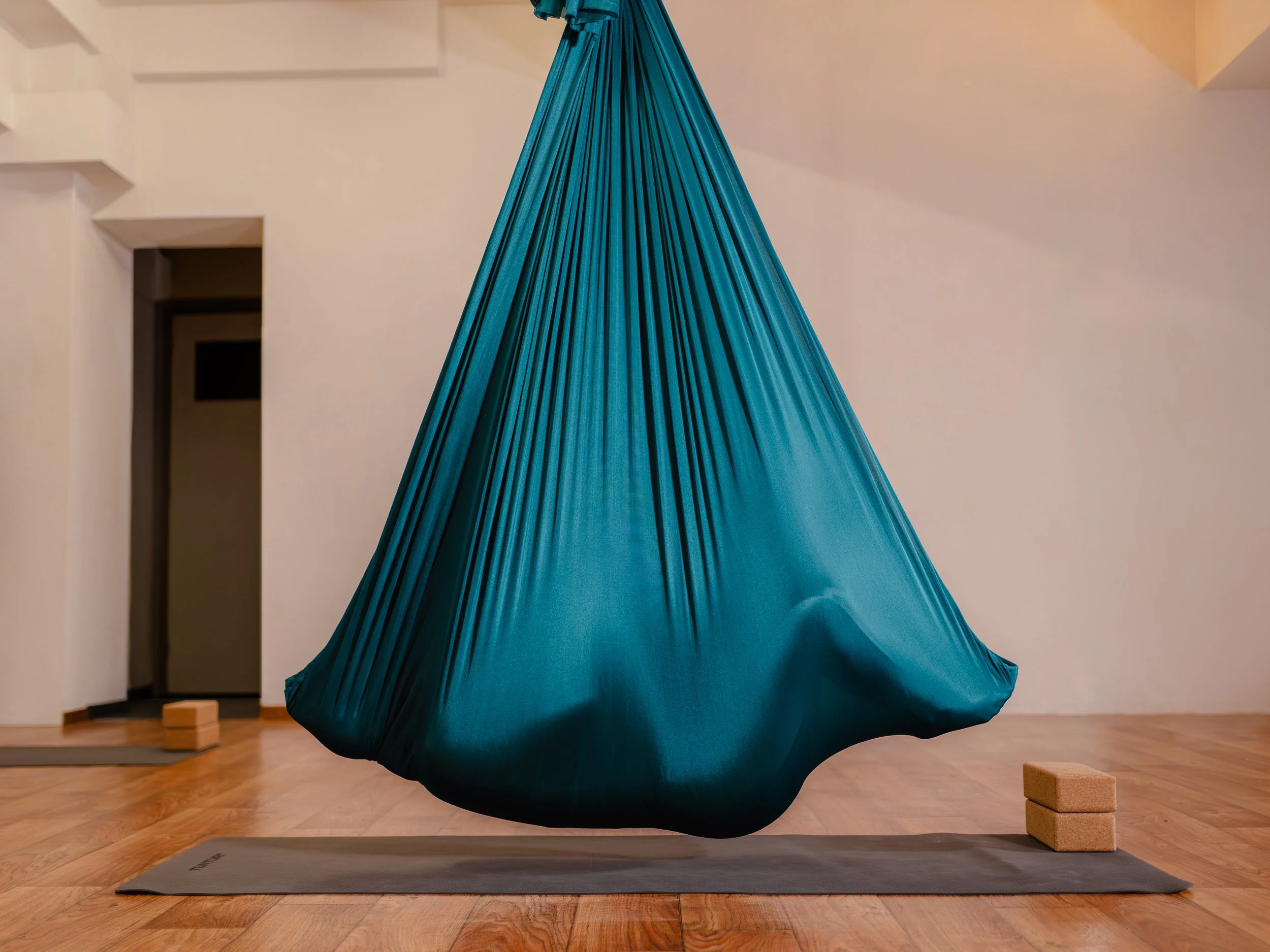 Aerial yoga in een parachute stoffendoek in het groen met een vrouw in het doek die relaxt.