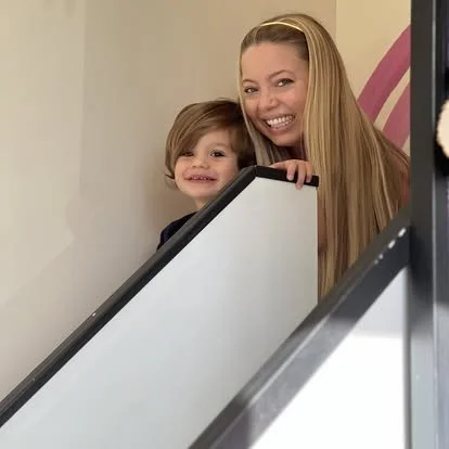 A woman and a young girl standing on an escalator, smiling at the camera.