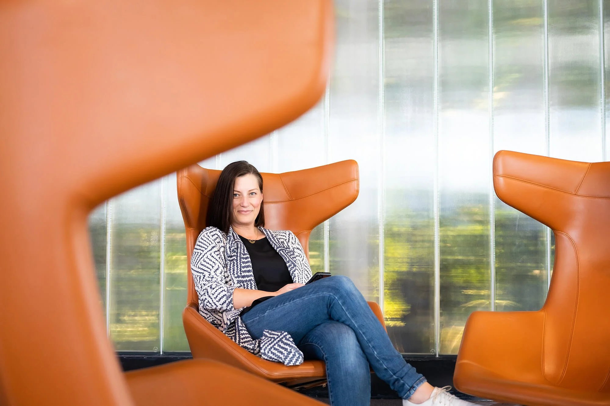 Meditation teacher sitting in orange wingback chair, smiling