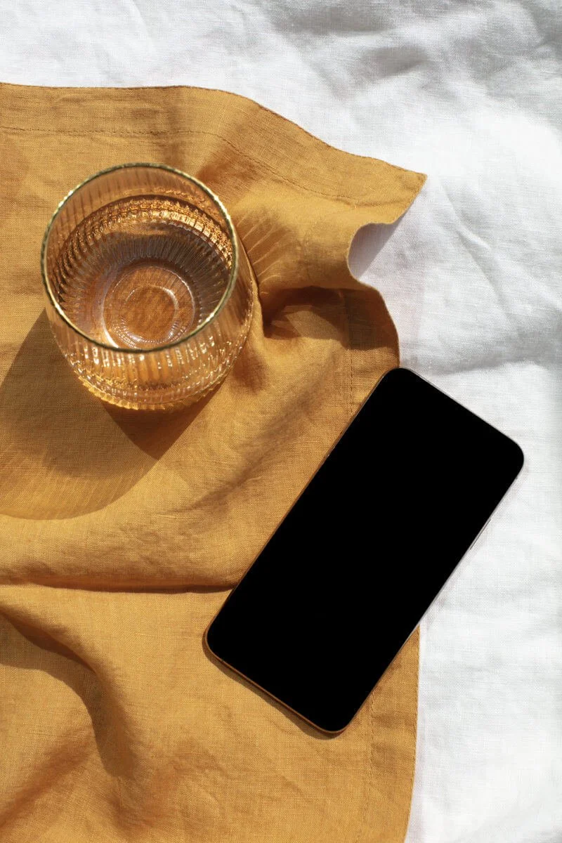 Glass and mobile phone on linen cloth