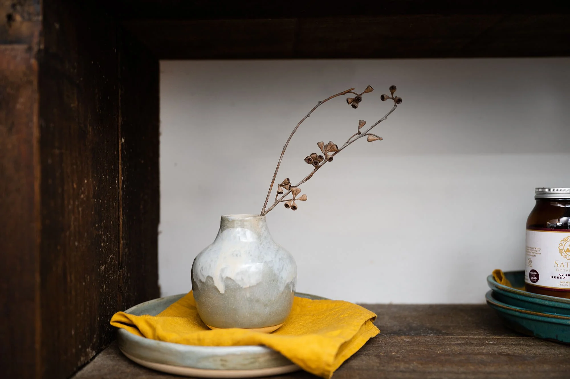Ceramic vase with dried wattle twigs, on shelves