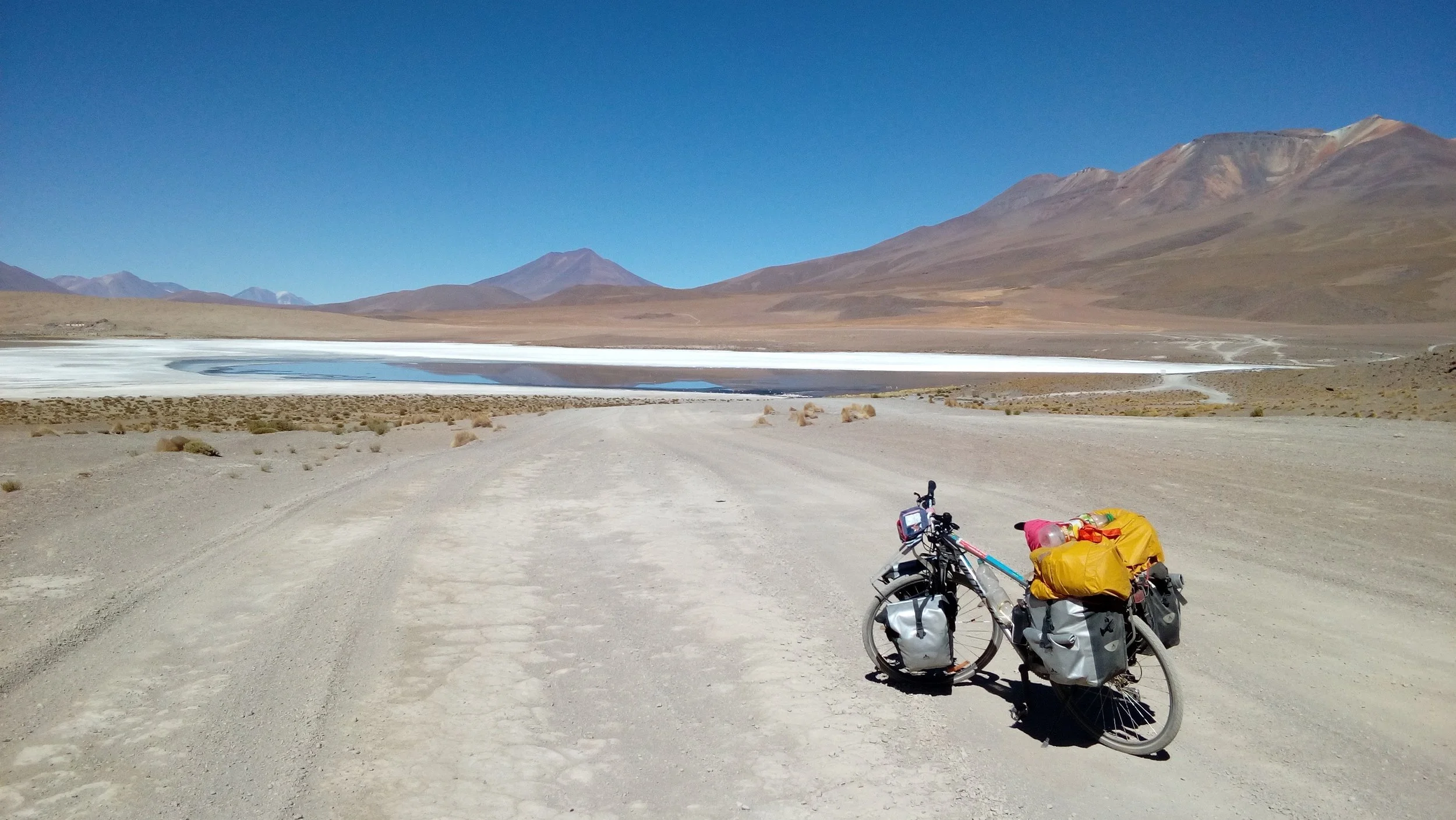Un vélo chargé avec des sacs et des équipements, stationné sur une route désertique. Photo de mes voyages