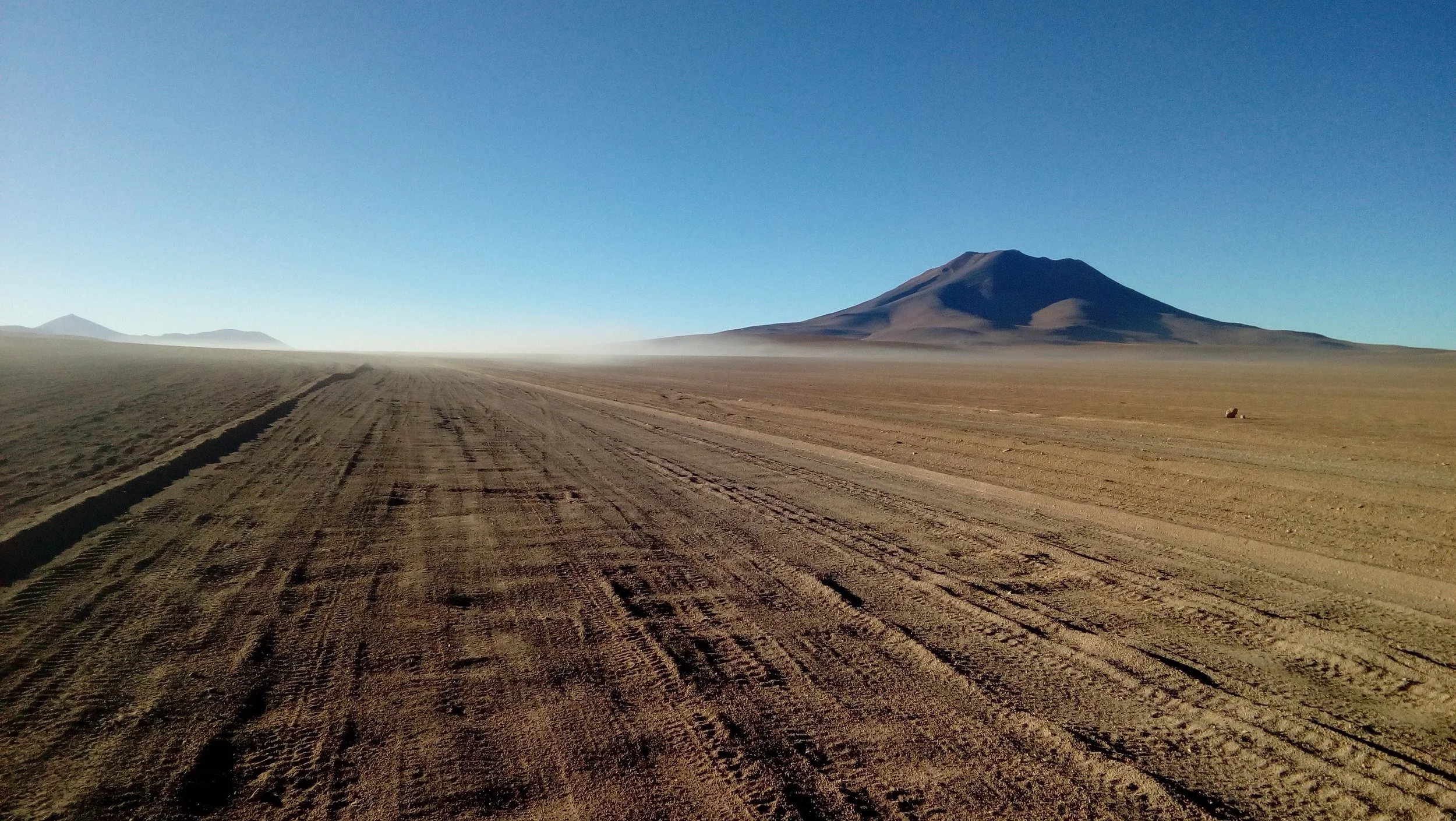 Une route de terre dans un désert avec des montagnes en arrière-plan. Voyage 