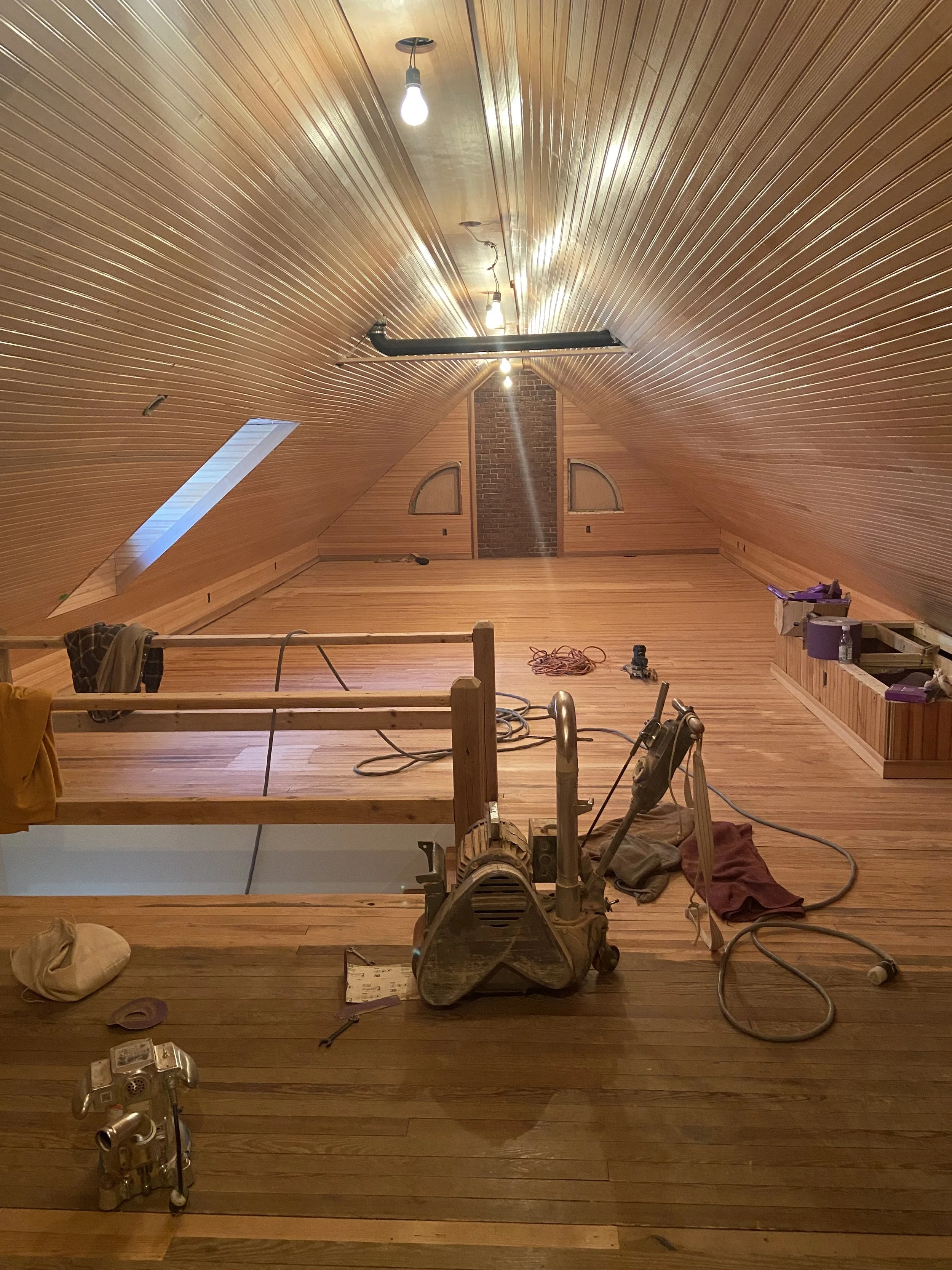 Pine floor sanding in process during an attic renovation.