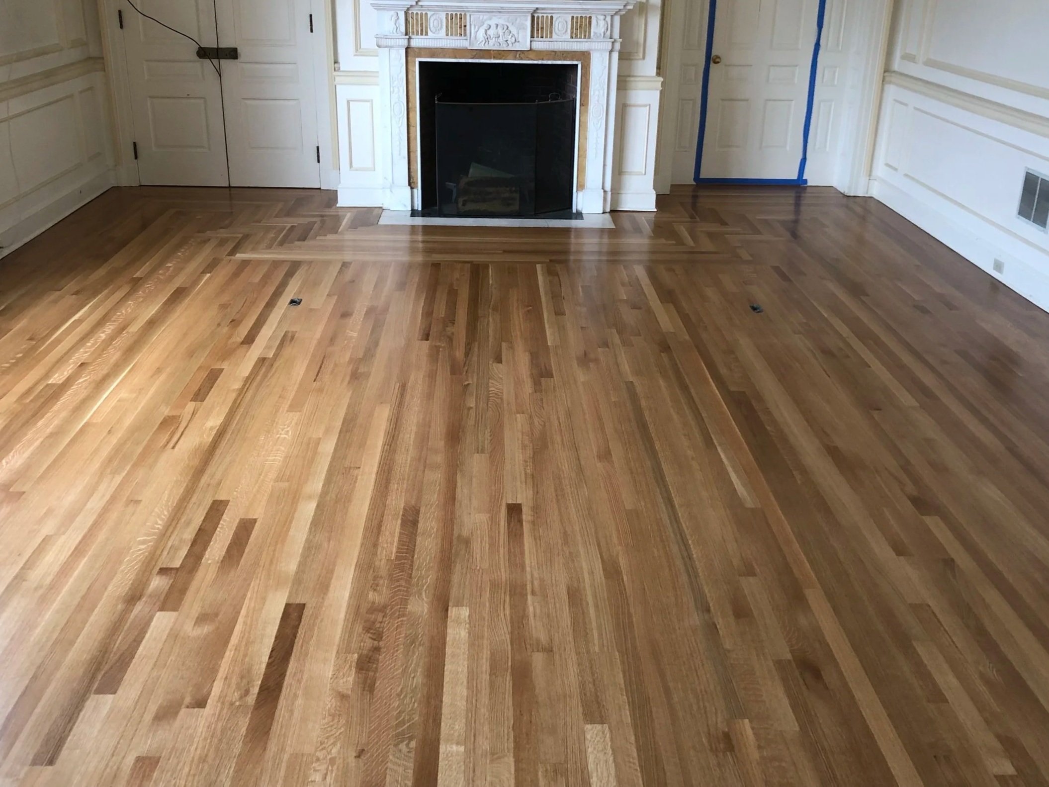 Newly installed white oak floors with a custom fireplace border in Lenox, Massachusetts.