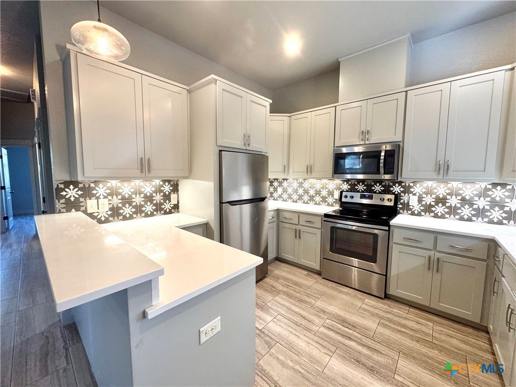 Modern kitchen with white cabinets, stainless steel appliances, and decorative tile backsplash.