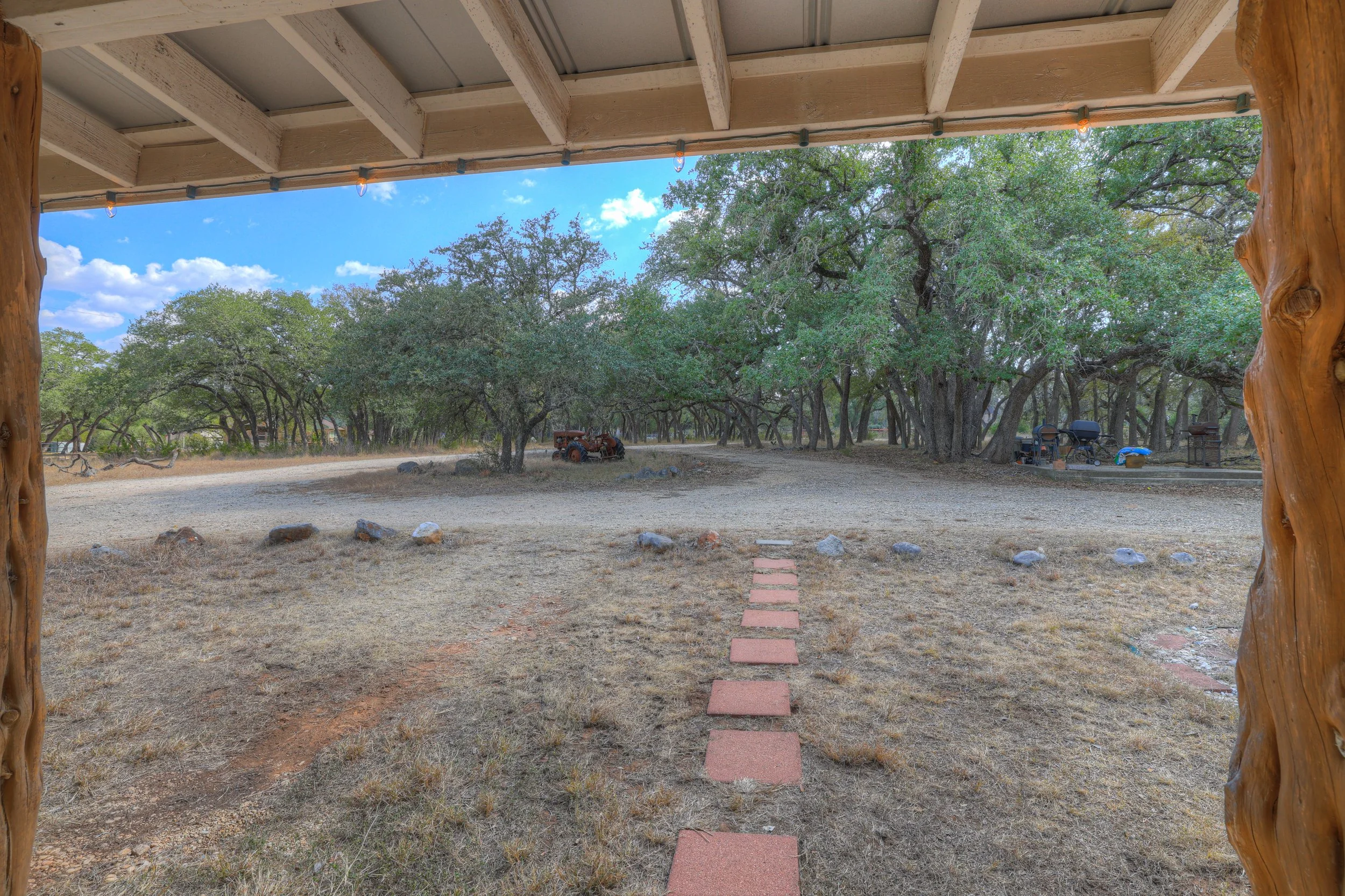 View of a backyard with a stepping stone path, trees, and a clear blue sky