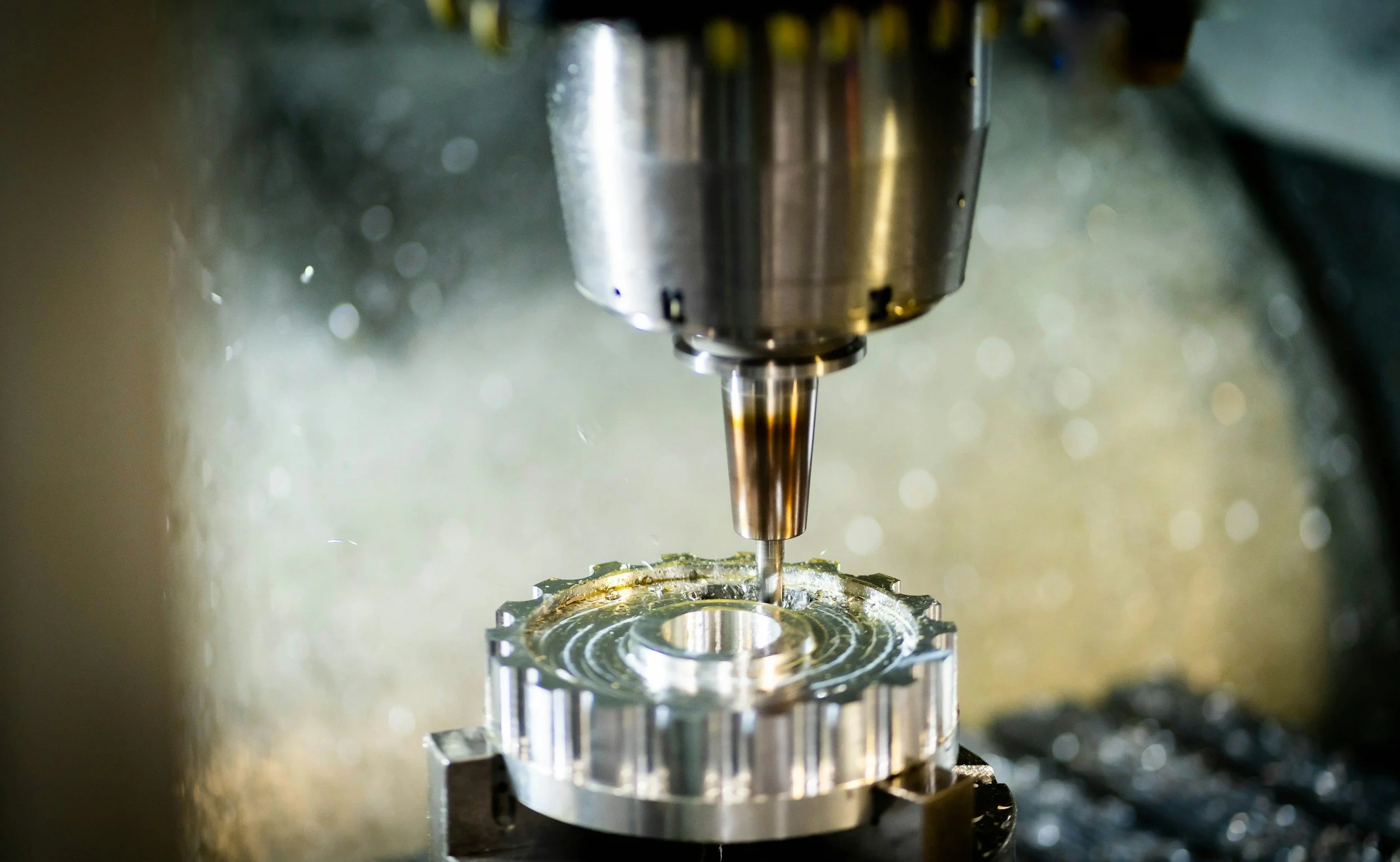 Close-up of a CNC machine drilling into a metallic circular component.