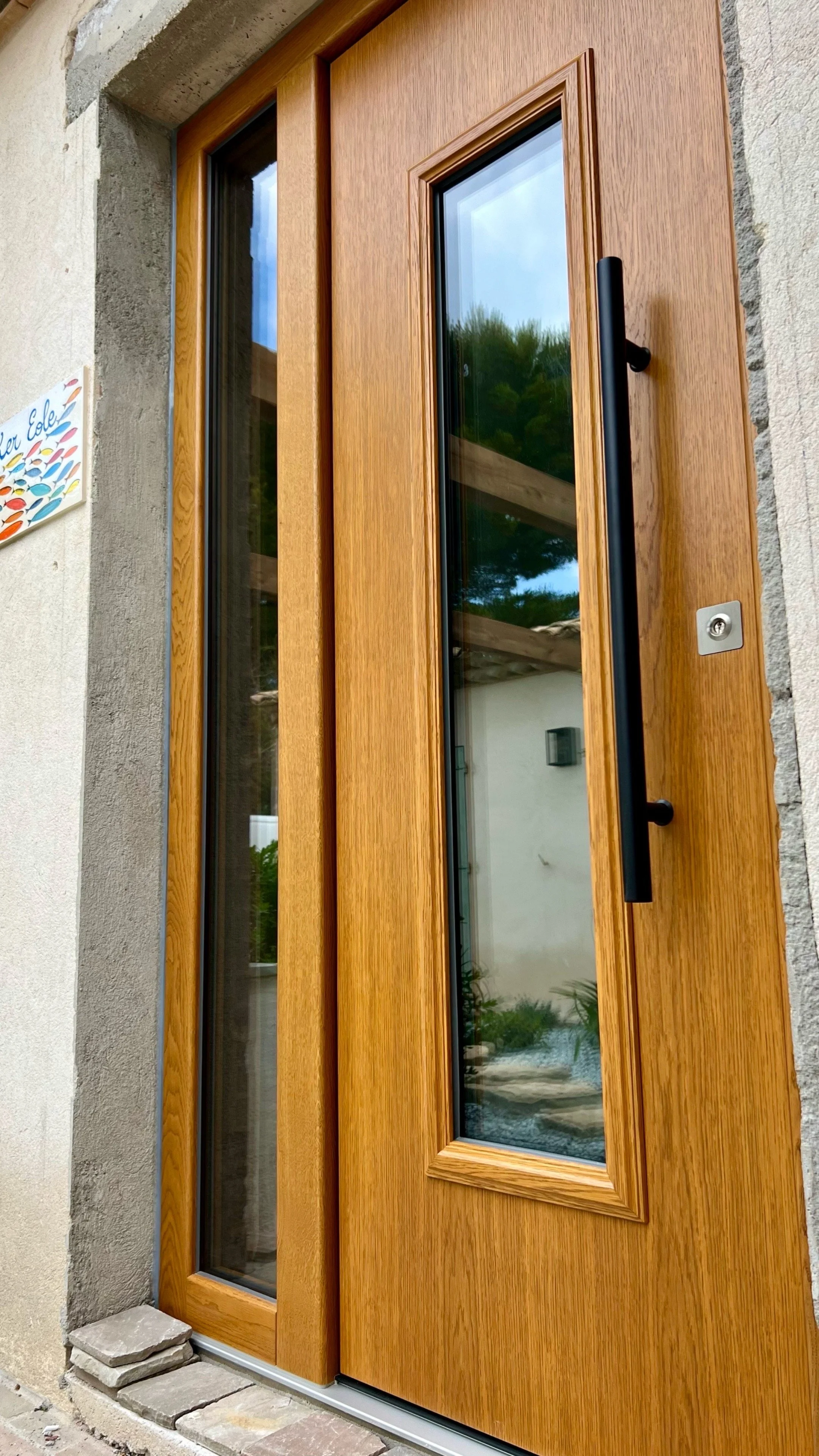 Porte en bois avec fenêtre en verre et poignée noire, façade de maison