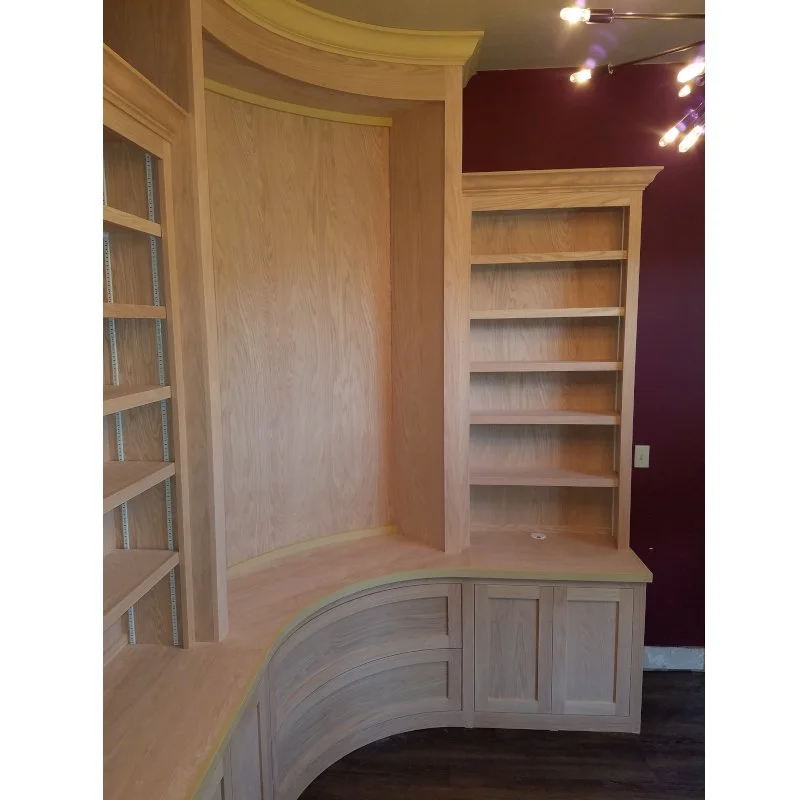 Custom wooden shelves and cabinetry in a room with a burgundy wall and a modern light fixture.