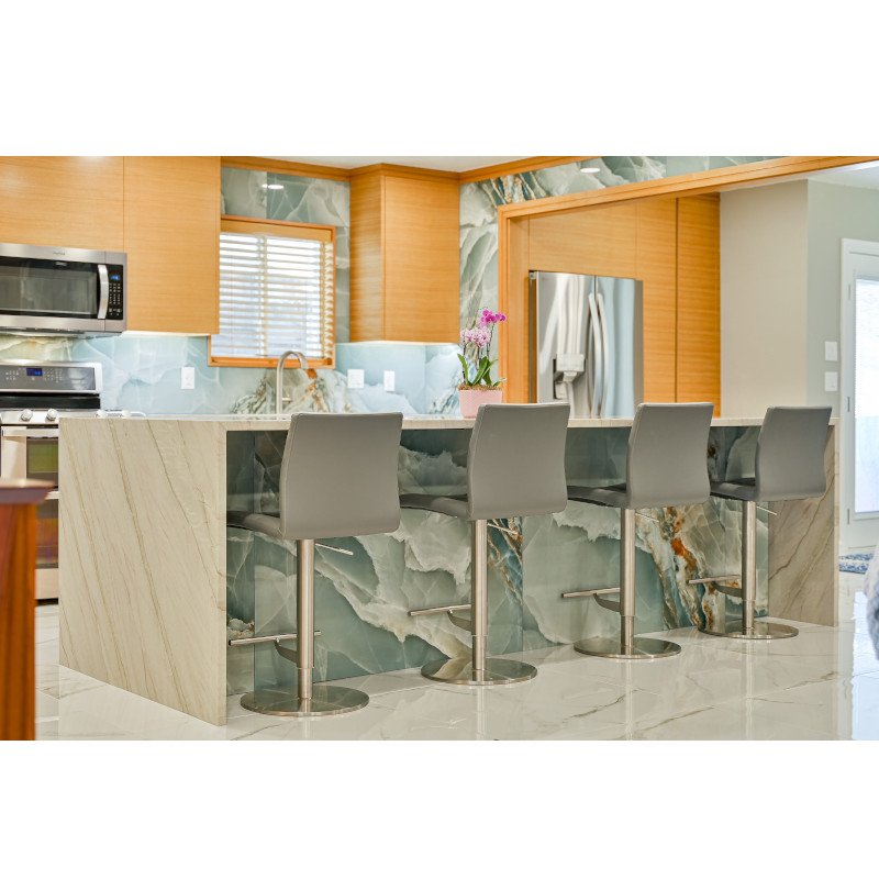 Modern kitchen with quartzite island, gray bar stools, wooden cabinets, and stainless steel appliances.  The cabinets have horizontal rift sawn white oak faces.