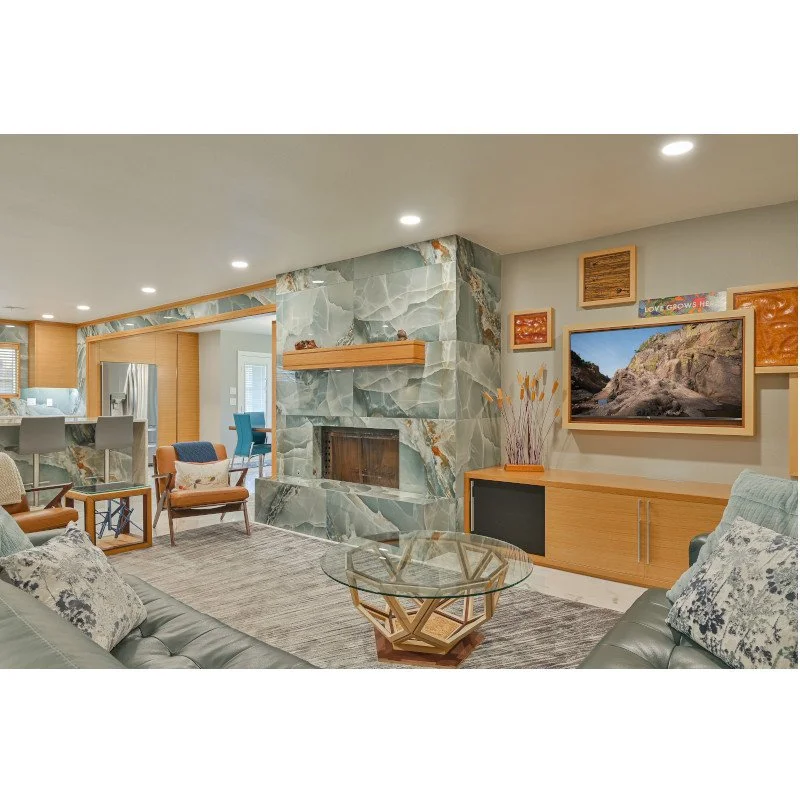 Living room with a marble fireplace, wooden furniture, a wall-mounted TV, and a glass coffee table.