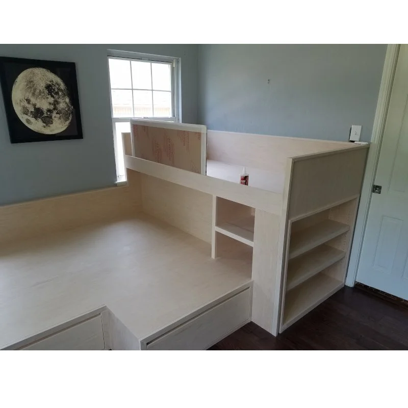 Room with built-in wooden bunk bed and storage shelves, window, and moon picture on the wall.