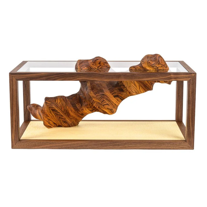 Wooden sculpture mounted inside a wooden frame coffee table with a glass top.