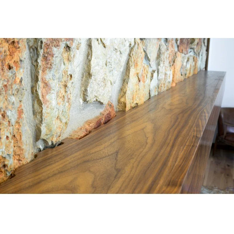 Close-up of a wooden shelf with a stone wall background.