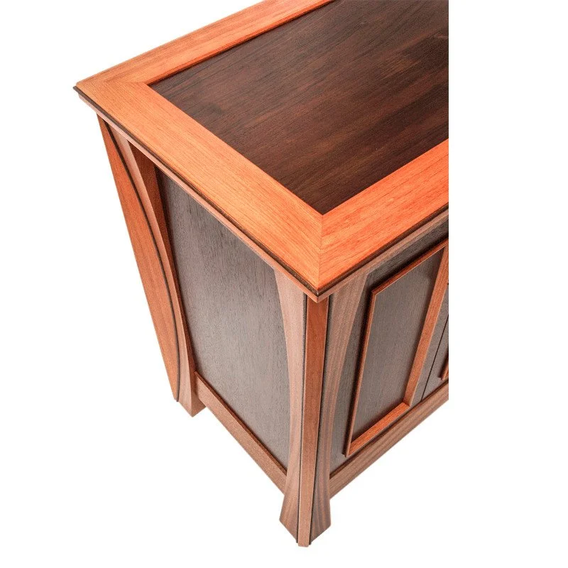A wooden cabinet with a dark top, reddish frame, and Peruvian walnut panel doors in an angled view.