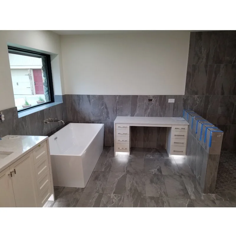 Bathroom under construction with a bathtub, a window, and an unfinished vanity area.