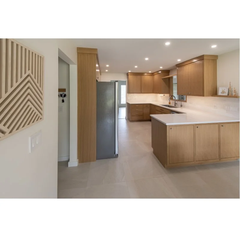 Modern kitchen with wooden cabinets, white countertops, stainless steel refrigerator, and recessed ceiling lights