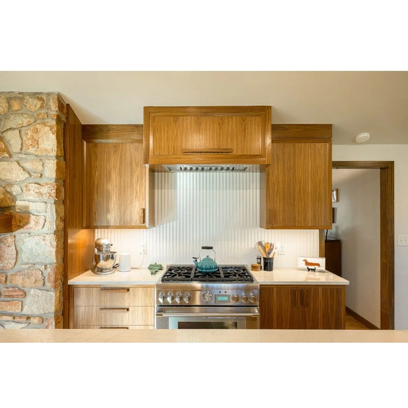 Kitchen with wooden cabinets, a stainless steel stove with a teal kettle, and decorative items on the counters.