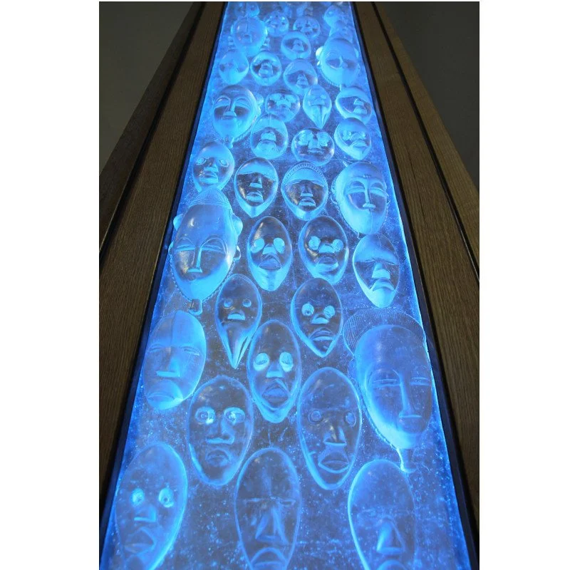 Art glass display of tribal masks illuminated with blue LED light in custom wood frame.