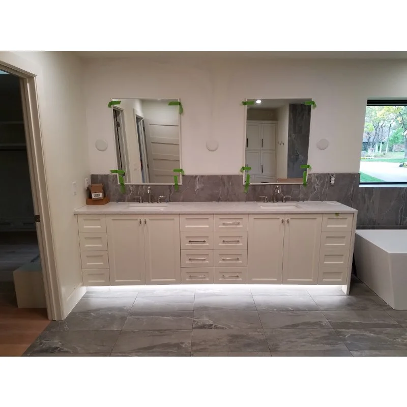 Bathroom vanity with two mirrors, cabinetry, and tap fixtures.