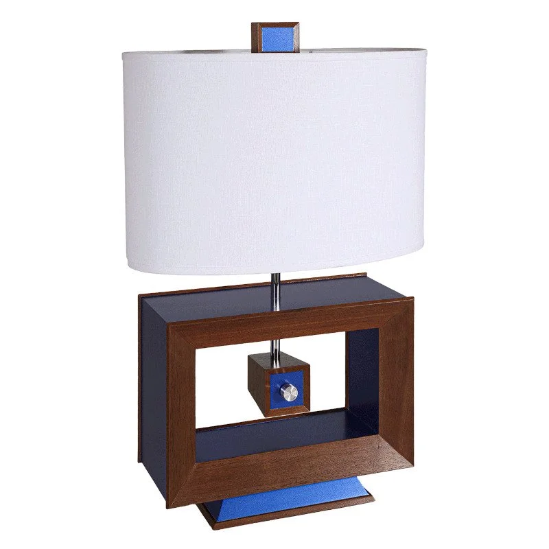 A table lamp with a rectangular blue and brown base, a chrome shaft, a white fabric lampshade, and a small decorative element at the top of the shade.
