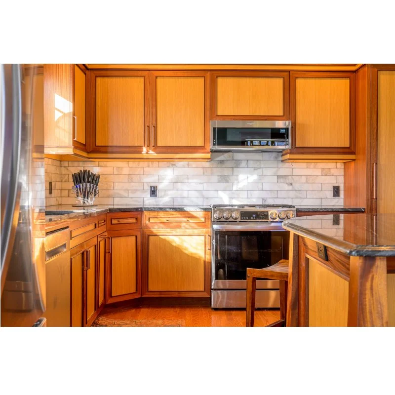 Kitchen with wooden cabinets, microwave over stove, and marble backsplash.