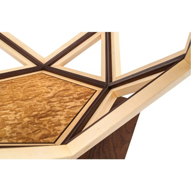 Close-up of a geometric wooden table with intricate inlay work, featuring light and dark wood accents.