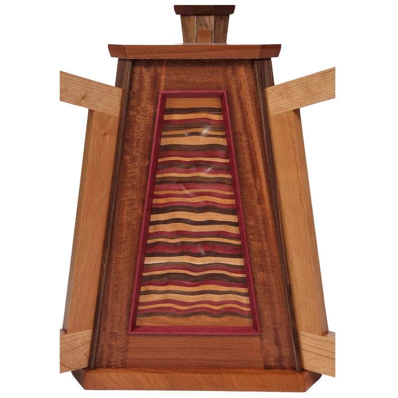 A wooden table with a glass top featuring a colorful, wavy carved striped pattern.