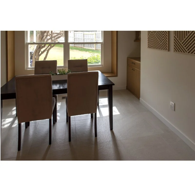 Dining room with four beige upholstered chairs around a dark wooden table near a window with a view of a tree and yard outside.