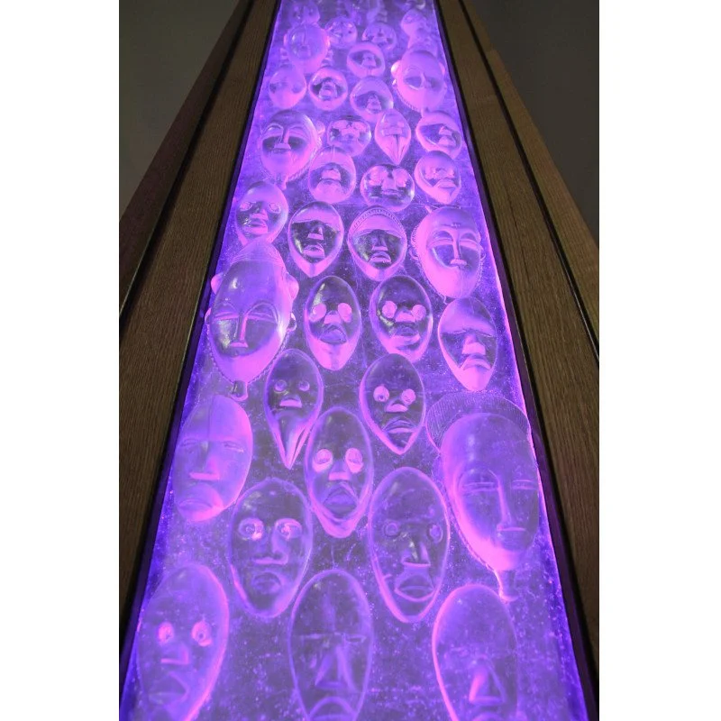 Art glass display of tribal masks illuminated with purple LED light in custom wood frame.