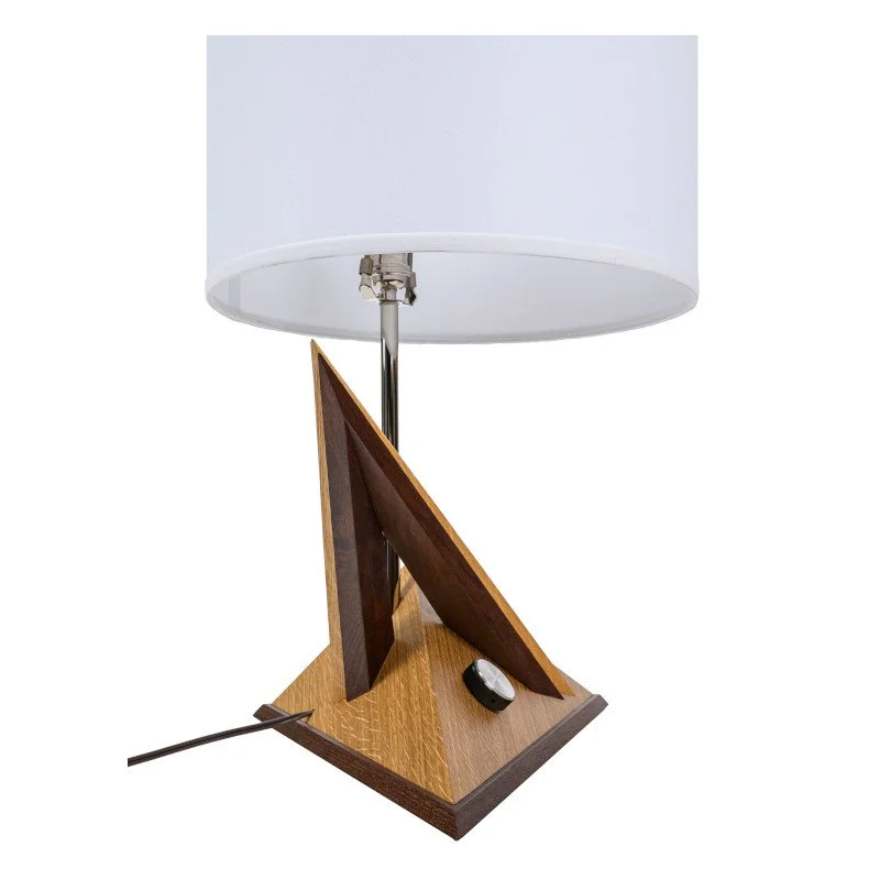 A table lamp with a white lampshade, a wooden and metal base, and a small metal power switch knob on the base.