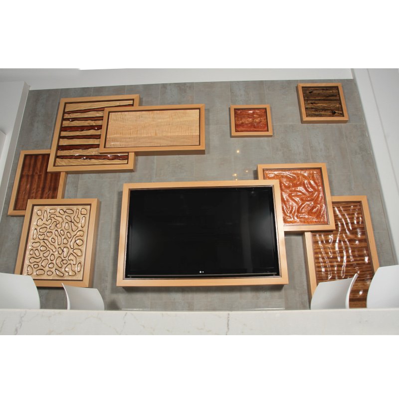 A wall with various wooden art pieces and a large flat-screen TV in the center.