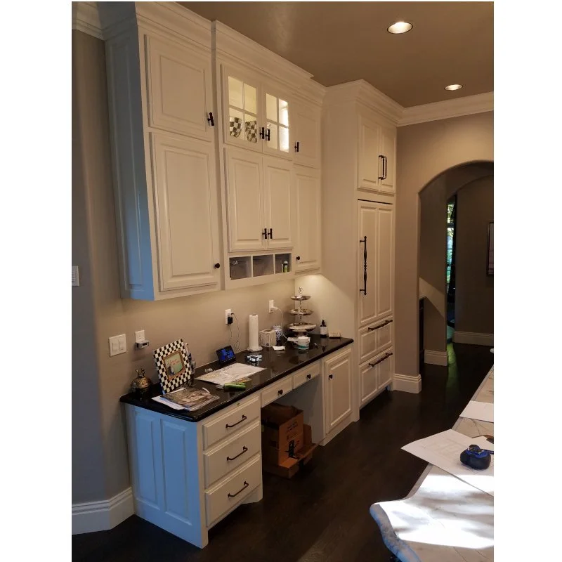 Kitchen with white cabinets, dark countertop, and various items on the counter.