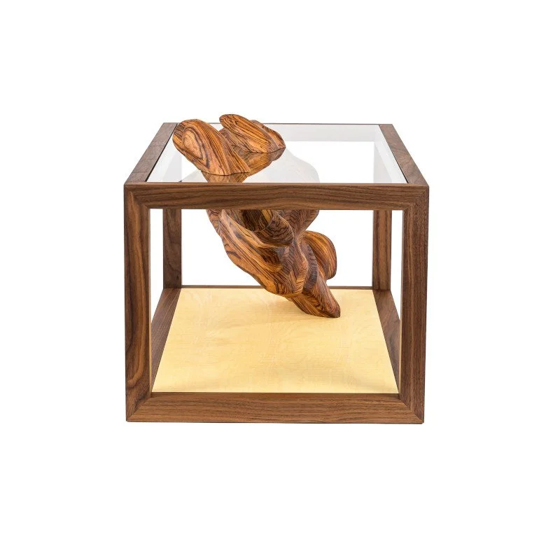 A decorative wooden sculpture inside a glass top coffee table.