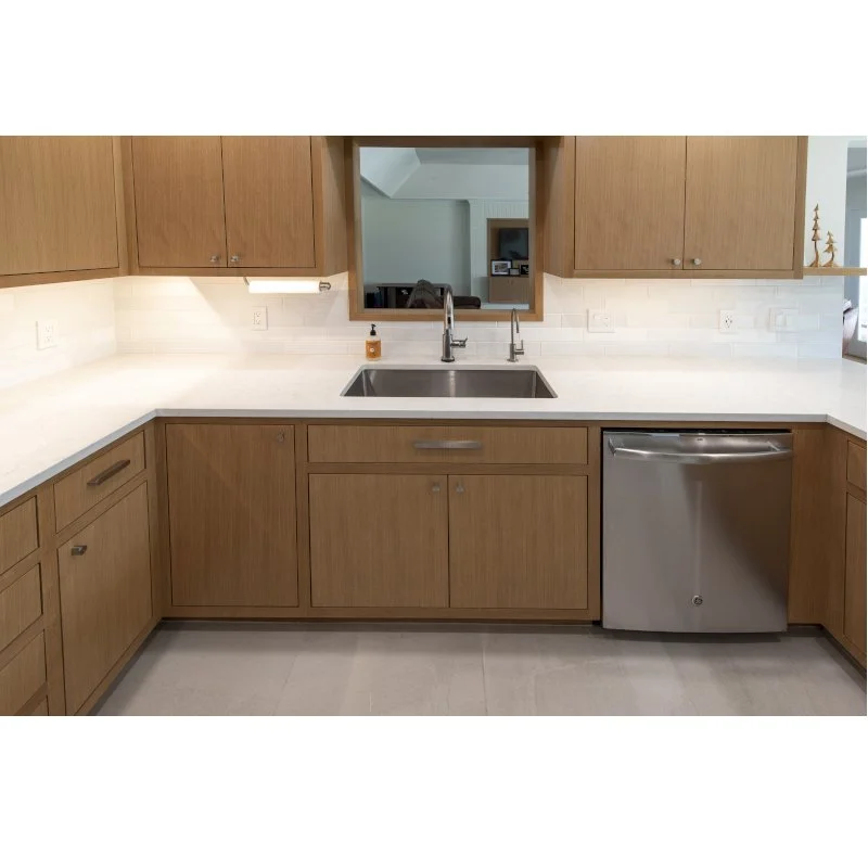 Kitchen with wooden cabinets, white countertop, stainless steel dishwasher, and a dual sink with a soap dispenser.
