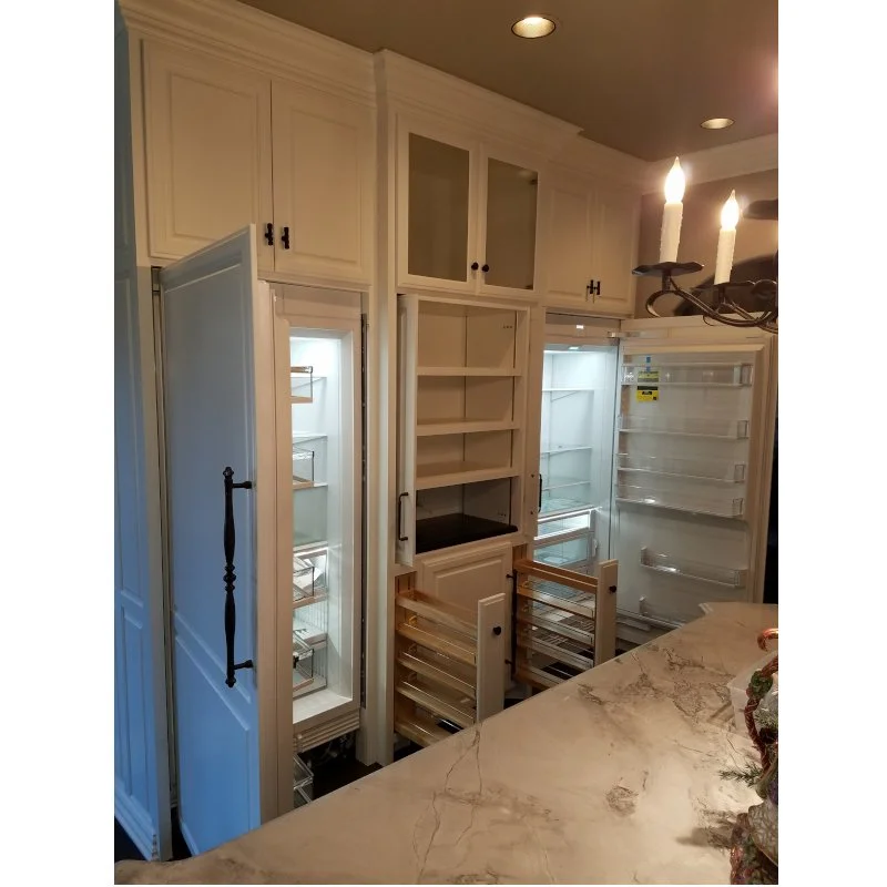 Empty kitchen cabinets and appliances, including two open refrigerators and empty shelves, completed with a marble countertop in a modern kitchen.