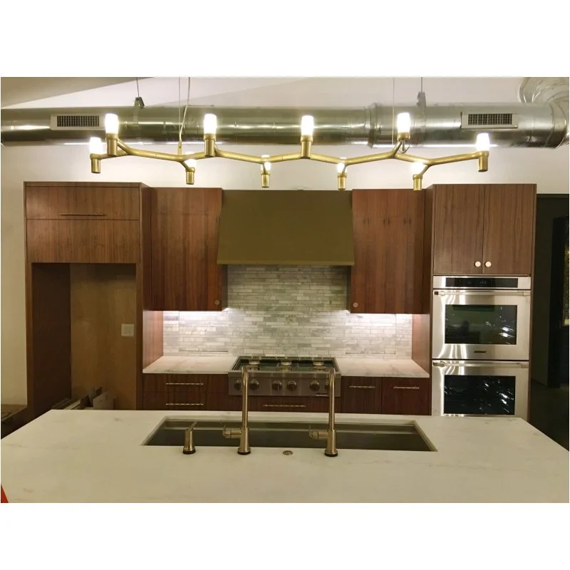 Modern kitchen with wooden cabinets, stainless steel appliances, a marble countertop, and a gold chandelier.
