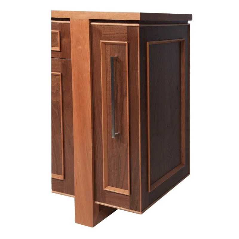 Close-up of a wooden kitchen cabinet with raised panel doors and a dark wood finish.