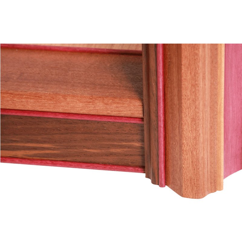 Close-up of a wooden coffee table with detailed molding and reddish wood trim.