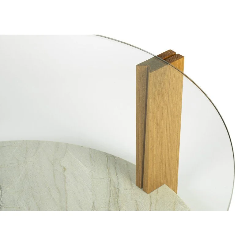 Close-up of a modern table with a circular marble surface, wooden leg, and a glass top.
