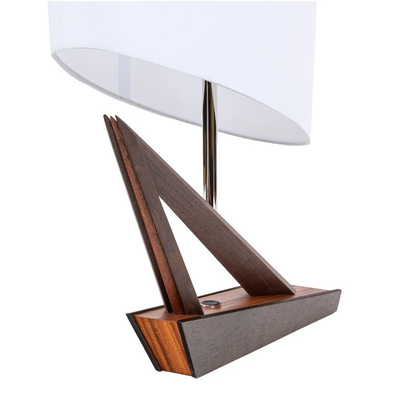 A modern table lamp with a white fabric shade, a metal pole, and a wooden base with geometric design.