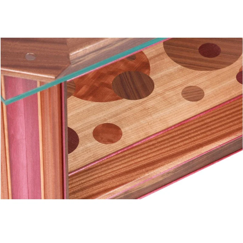 Close-up of a glass-top wooden table with circular inlays and a colorful striped edge.