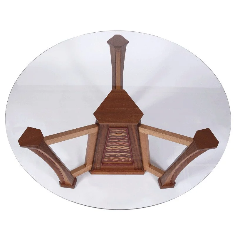 Top-down view of a wooden table with three curved legs and a patterned center panel.