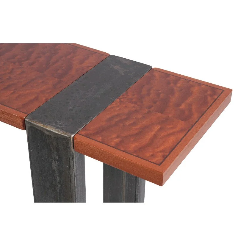 Close-up of a corner of a wooden table with a black metal strap.