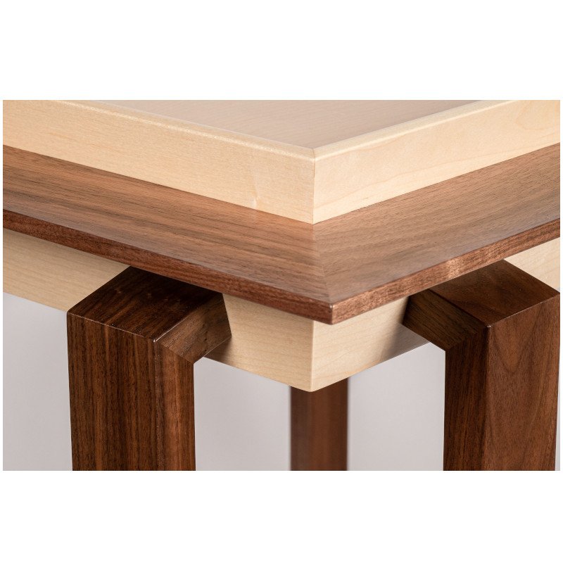 Close-up of a wooden table showing its layered wooden top and sturdy legs, with the layers in different shades of wood.