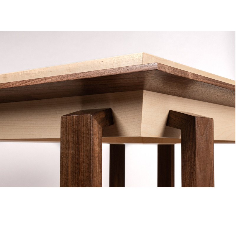 Close-up view of a wooden table with a light-colored tabletop and dark wooden legs.