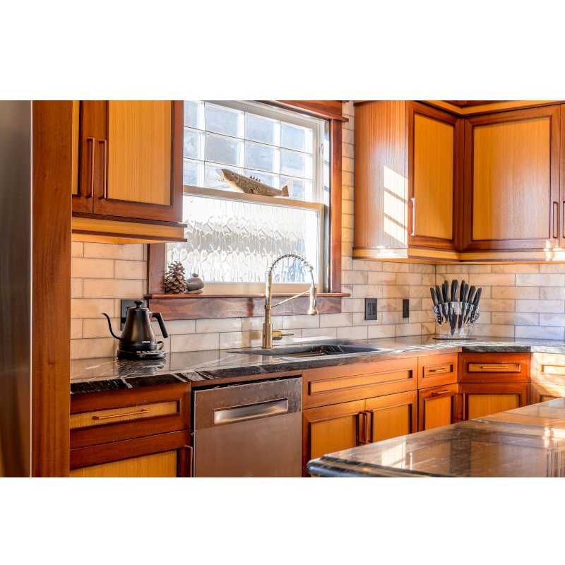 Kitchen with wooden cabinets, a window above the sink, and a black kettle on the counter.