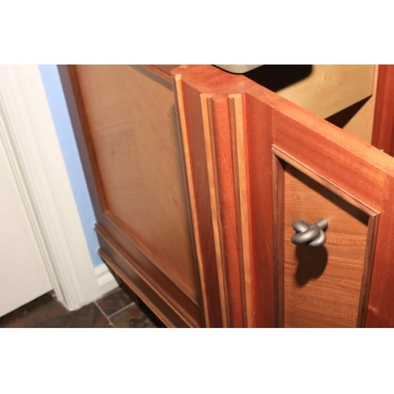 Close-up of a wooden cabinet with a metal knob, showing detailed wood grain and decorative trim.