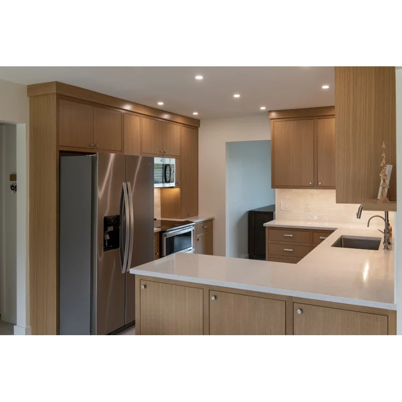 Modern kitchen with wood cabinets, stainless steel refrigerator, microwave, and white countertops.